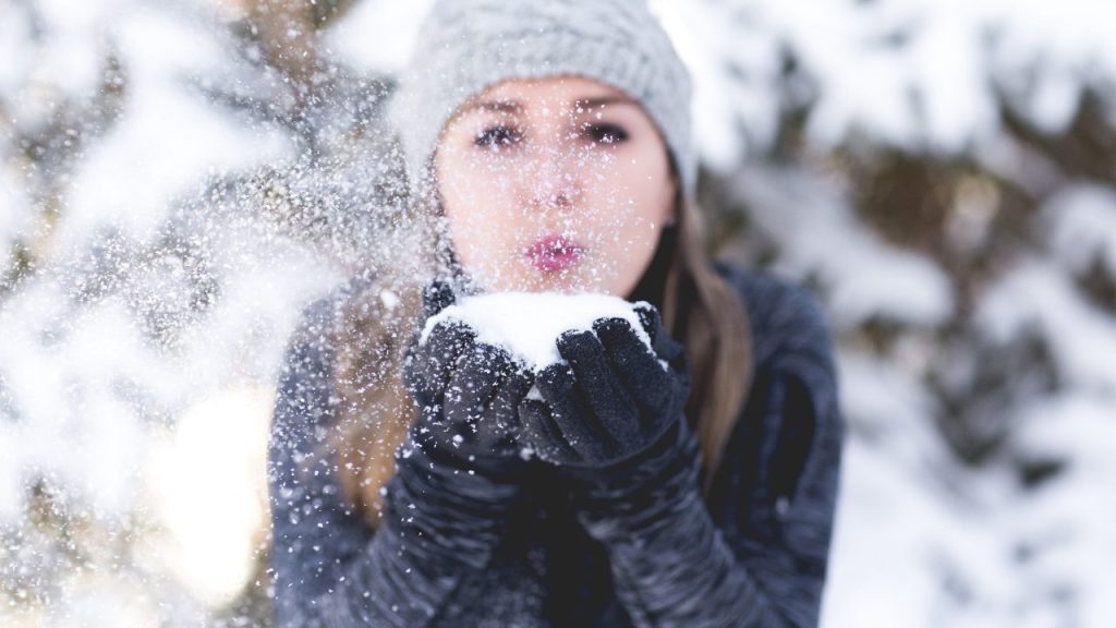 雪を吹きかける女性