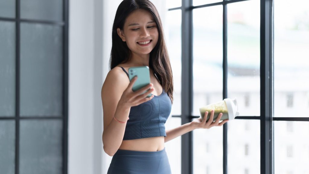 スマートフォンをいじりながらプロ店を飲む女性